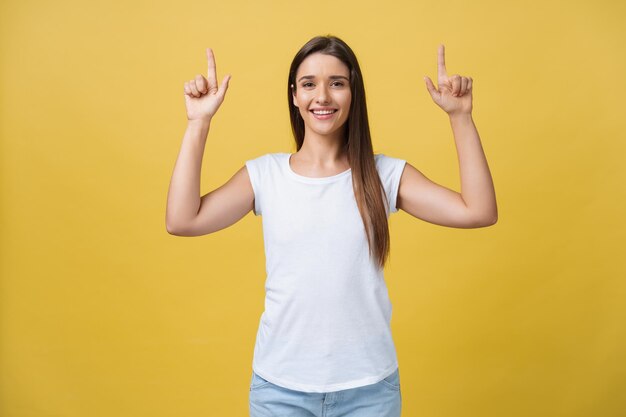 Surprenez la jeune femme pointant d'un côté avec son doigt tout en ouvrant la bouche sur un fond jaune