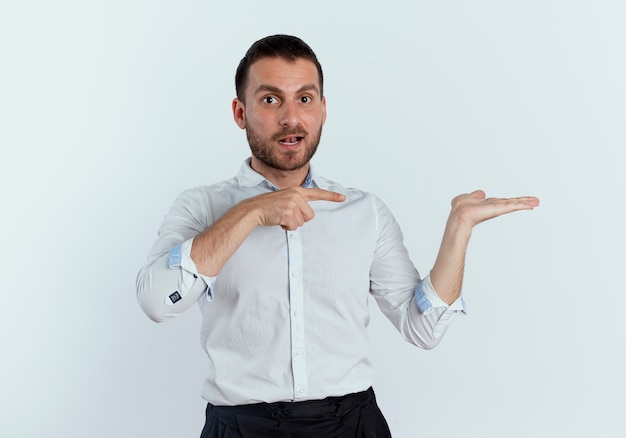 Surpris bel homme pointe la main vide isolé sur un mur blanc