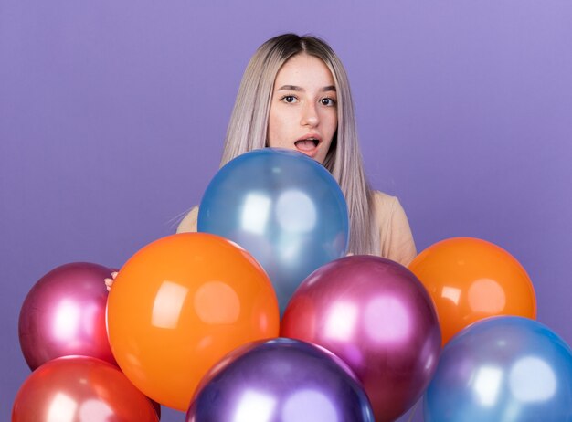 Surpris belle jeune fille debout derrière des ballons