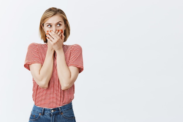 Surpris curieux jolie fille ferme la bouche et à droite amusé