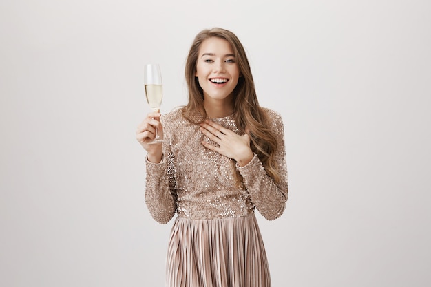 Surpris femme souriante en robe de soirée, boire du champagne
