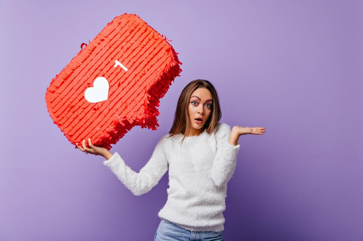 Photo gratuit surpris fille bien habillée posant avec une bannière rouge. portrait intérieur d'une blogueuse émotionnelle en pull moelleux.