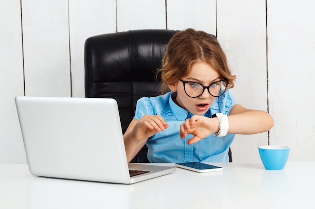 Surpris jeune belle fille regardant sur montre au lieu de travail.