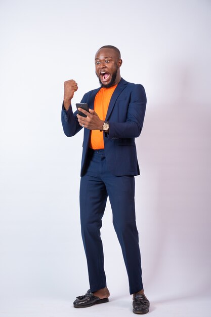 Surpris jeune homme d'affaires nigérian célébrant en regardant son téléphone
