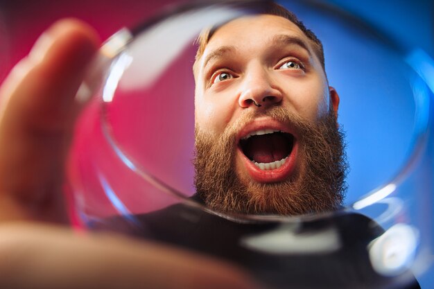 surpris jeune homme posant avec un verre de vin. Visage masculin émotionnel