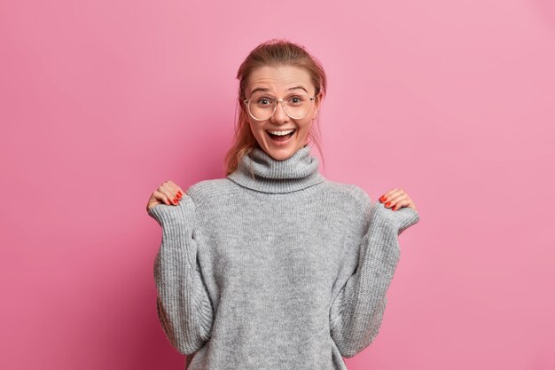 Surpris joyeuse jeune femme européenne lève les mains et regarde avec excitation entend quelque chose d'excellent