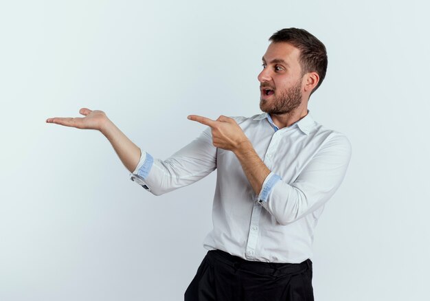 Surpris les points de bel homme et regarde la main vide isolée sur le mur blanc