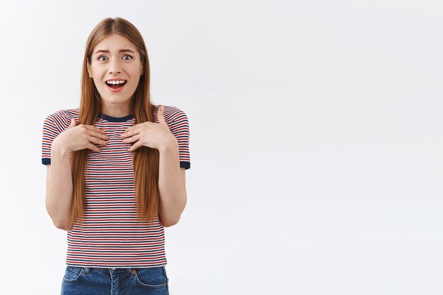 Surprise et flattée agréable jeune fille européenne en t-shirt rayé, appuyez les paumes sur la poitrine et soupirant d'amusement et de sympathie, souriant avec plaisir, recevez un cadeau génial, restez sur fond blanc