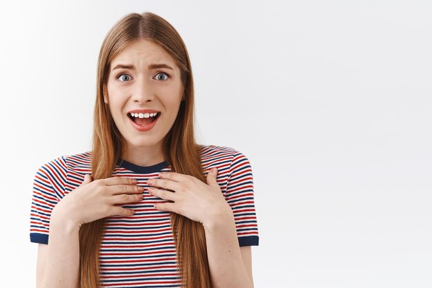 Photo gratuite surprise reconnaissante belle jeune femme en t-shirt rayé tenir la main sur la poitrine impressionnée et choquée bouche ouverte haletant flatté souriant heureux et ravi fond blanc