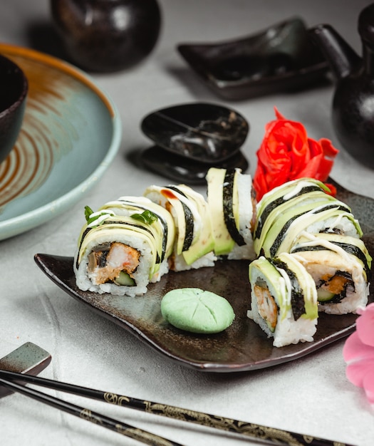 Sushi roule dans une assiette noire avec des baguettes.