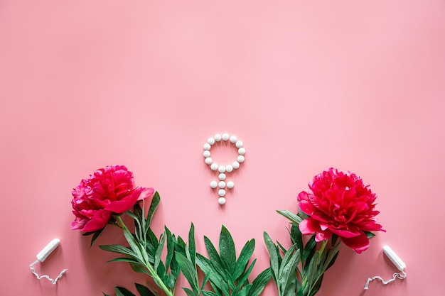 Photo gratuite symbole de genre vénus composé de pilules et de fleurs de pivoine sur fond rose