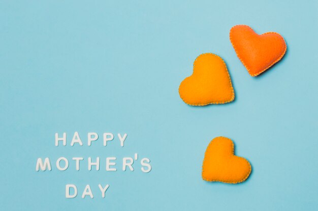 Symboles décoratifs de coeur près de titre de fête des mères heureux
