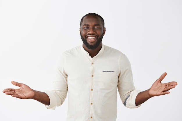 Photo gratuite sympathique beau jeune homme posant contre le mur blanc