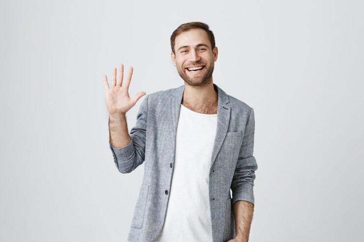 Photo gratuit sympathique souriant beau mec en agitant la main pour saluer, dire bonjour