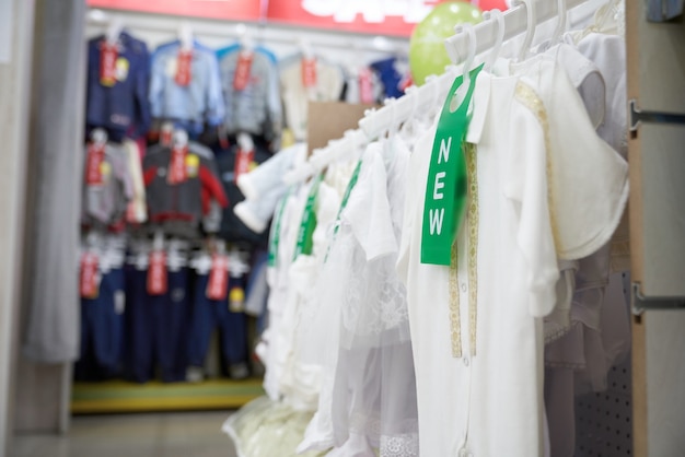 T-shirt blanc pour enfants sur des cintres dans un magasin de vêtements.