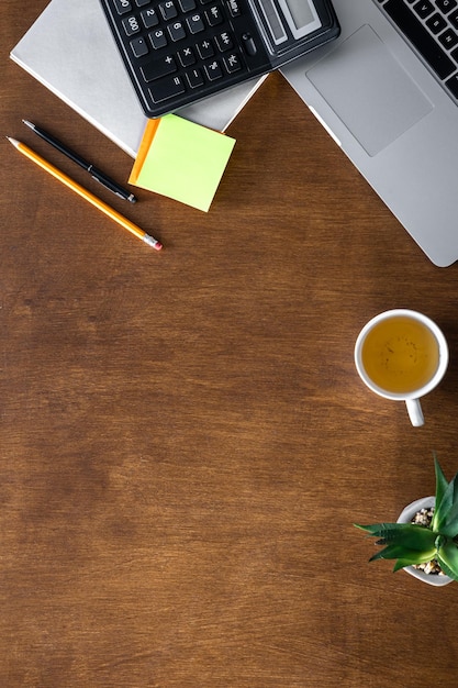 Photo gratuite table en bois de bureau plate avec bloc-notes et calculatrice de tasse d'ordinateur portable