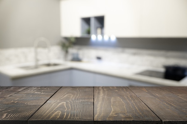 Table en bois vide et cuisine moderne défocalisée comme toile de fond pour la conception