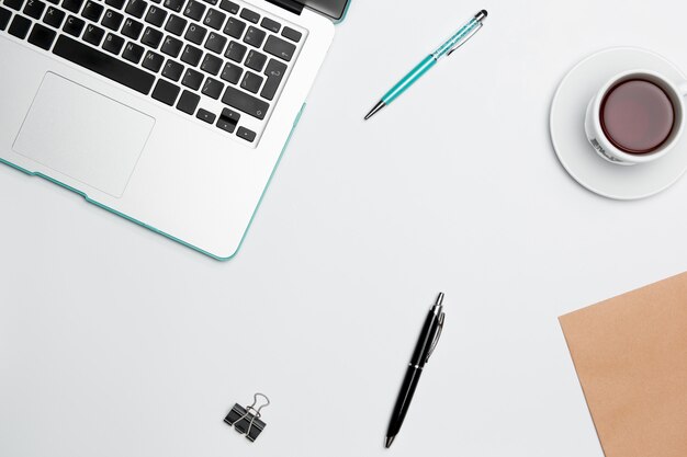 Table de bureau avec ordinateur, fournitures, fleurs et tasse à café