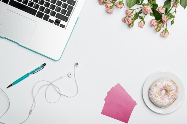 Table de bureau avec ordinateur, fournitures, fleurs