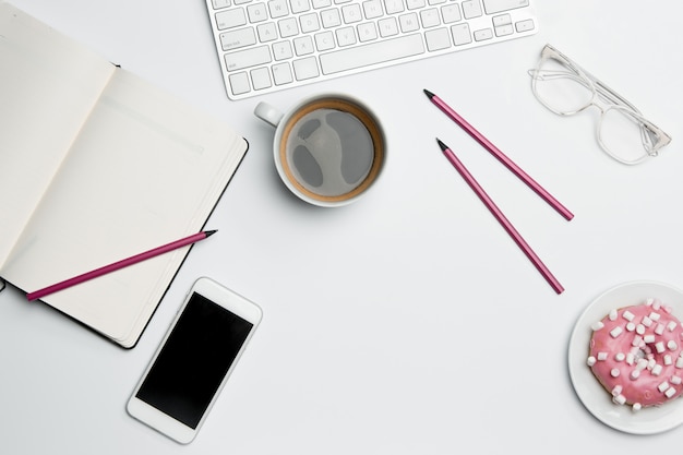 Table de bureau avec ordinateur, fournitures, téléphone et tasse à café.