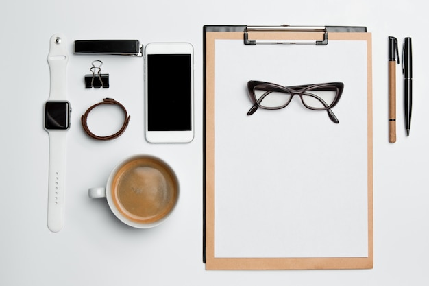 Table de bureau avec tasse, fournitures, téléphone sur blanc