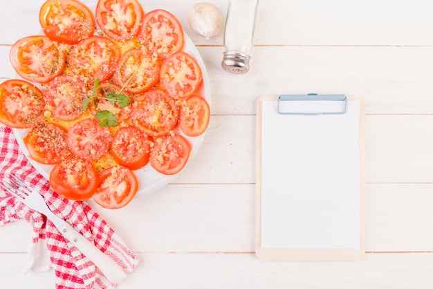 Photo gratuite table de cuisson avec assiette de tomates et presse-papiers