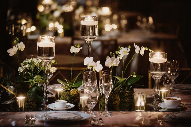 Table décorée d'orchidées et de bougies, verres à la lumière