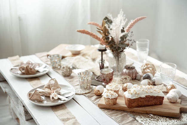 Une table de fête avec un cadre magnifique, des détails décoratifs, des œufs et un gâteau de Pâques.