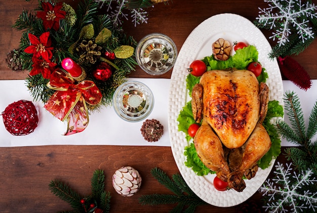 Table de Noël servie avec une dinde, décorée de guirlandes lumineuses et de bougies