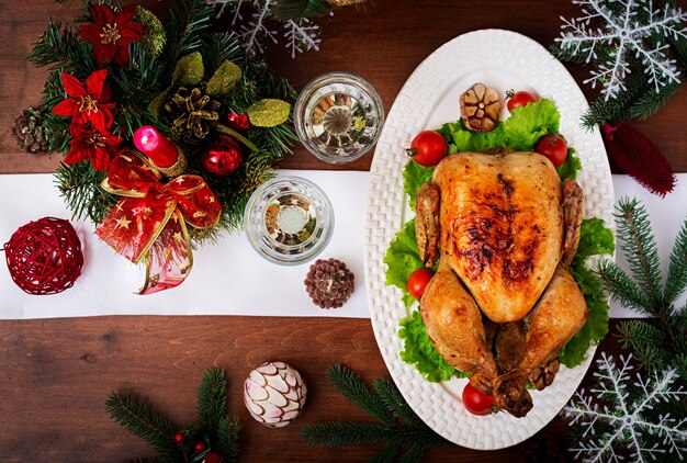 Table de Noël servie avec une dinde, décorée de guirlandes lumineuses et de bougies