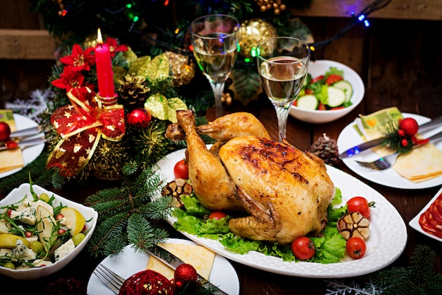 Table de Noël servie avec une dinde, décorée de guirlandes lumineuses et de bougies