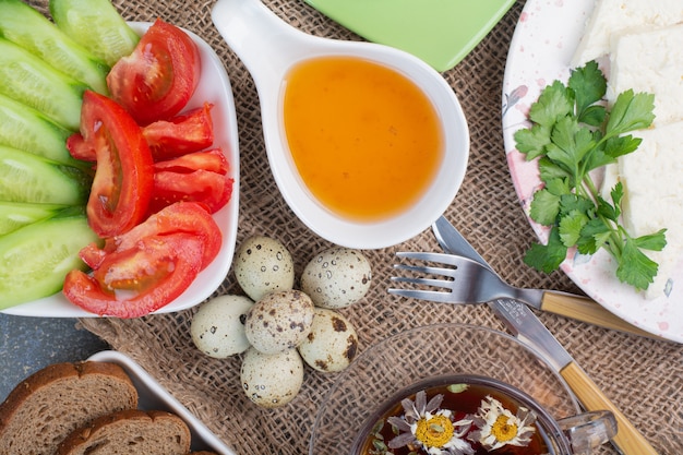 Table de petit-déjeuner avec légumes, thé, pain et œufs