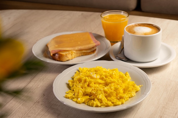 Table de petit-déjeuner avec œufs, tasse de café, jus d'orange et tranche de pain avec fromage et bacon.