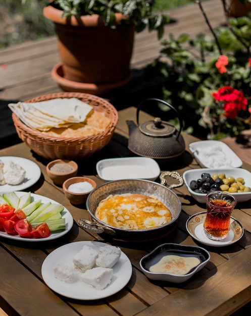 Table de petit déjeuner avec omelette, fromage, olives et légumes.