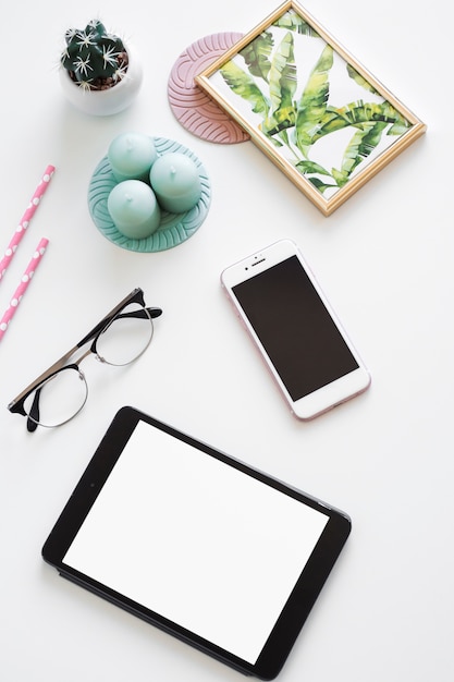 Table avec tablette près du smartphone, du cadre photo, des bougies et des lunettes