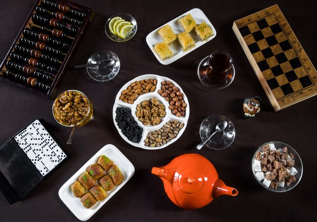 Table à thé avec verres à thé, noix et plateau de jeu.