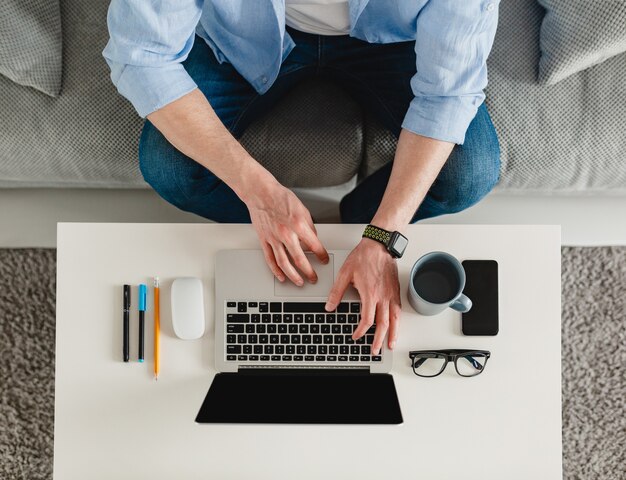 Table de travail de l'homme close-up mains à la maison de travail en tapant sur ordinateur portable