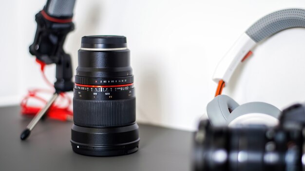 Table avec des trucs de créateur de contenu. Appareil photo, microphone, objectif de l'appareil photo et écouteurs. Travailler à domicile