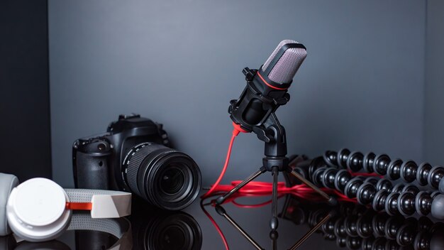 Table avec des trucs de créateur de contenu. Appareil photo, microphone, trépied et écouteurs. Travailler à domicile