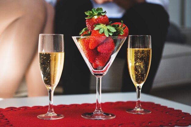 Table avec un verre avec des fraises et deux verres de champagne