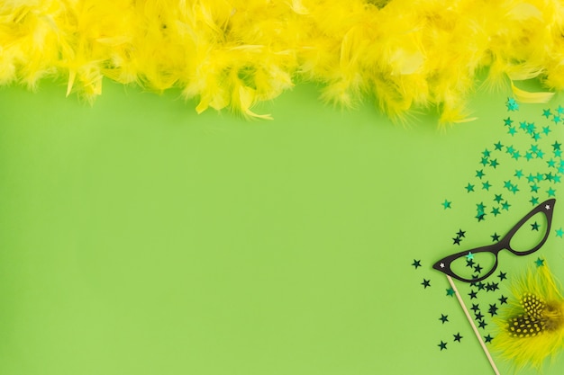 Table verte avec des plumes jaunes sur le dessus et des lunettes violettes