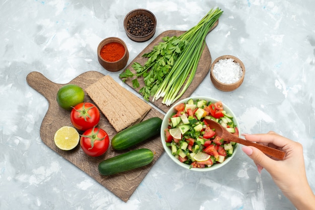 Table de vue lointaine du haut avec des légumes tels que des concombres de tomates et des chips de citrons et des légumes verts sur blanc, salade de légumes