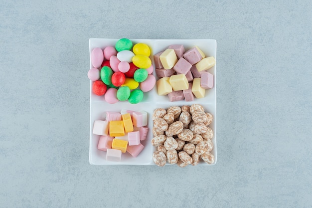 Un tableau blanc avec des guimauves et des bonbons colorés sur une surface blanche