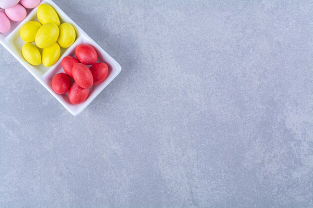 Un tableau blanc plein de bonbons aux haricots colorés sur une table grise.