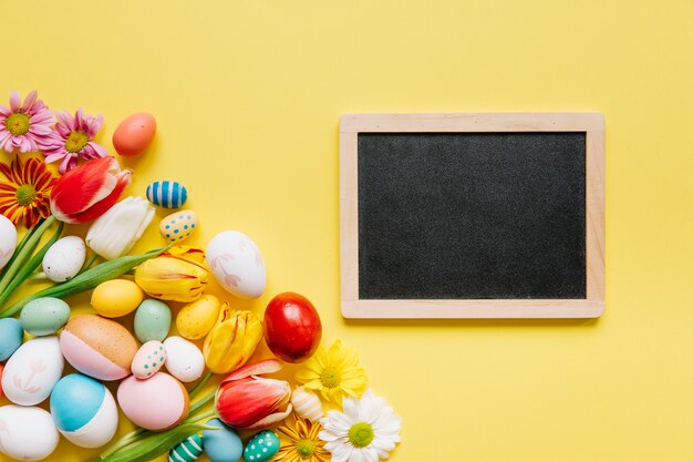 Tableau noir en arrangement avec des fleurs et des oeufs