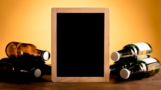 Tableau noir entre ensemble de bouteilles d&#39;alcool sur la table en bois