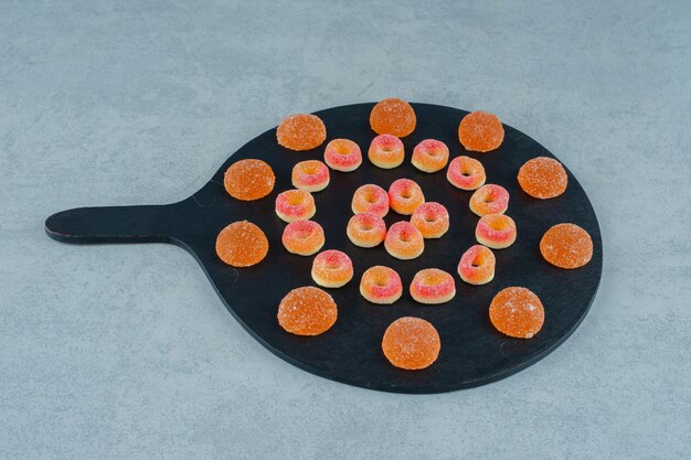 Un tableau noir plein de bonbons à la gelée d'orange ronds en forme d'anneaux et de bonbons à la gelée d'orange avec du sucre