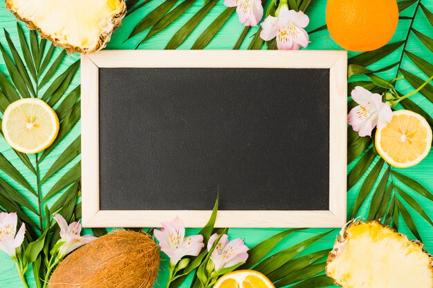 Tableau noir près des feuilles des plantes avec des fruits frais