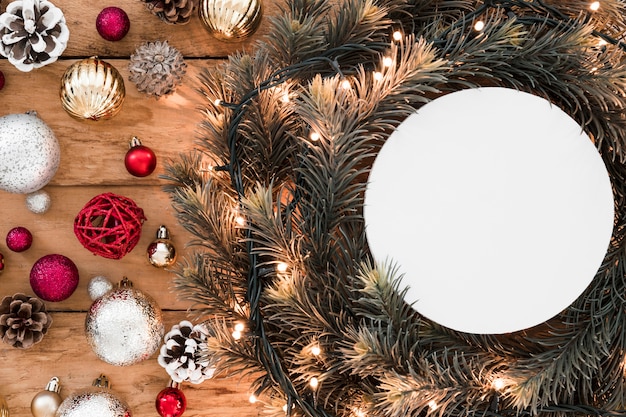 Photo gratuite tablette blanche entre des brindilles de sapin et des décorations de noël