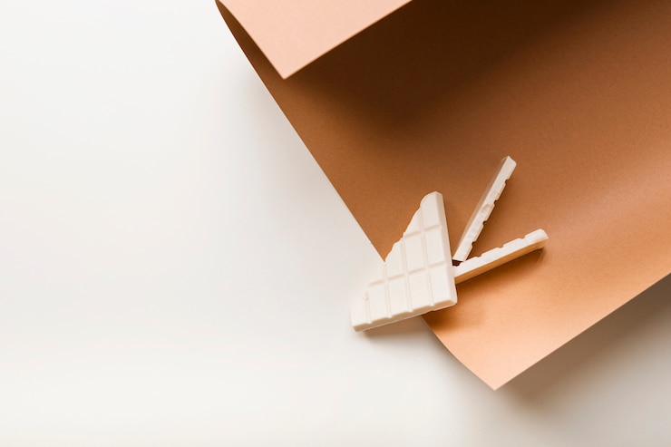 Photo gratuit tablette de chocolat blanc sur papier cartonné brun sur fond blanc